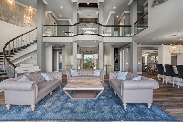 living room featuring dark hardwood / wood-style floors, a towering ceiling, and an inviting chandelier