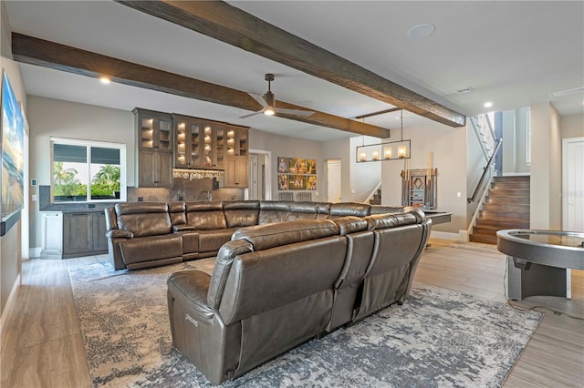 living room with beam ceiling, ceiling fan with notable chandelier, and light hardwood / wood-style floors