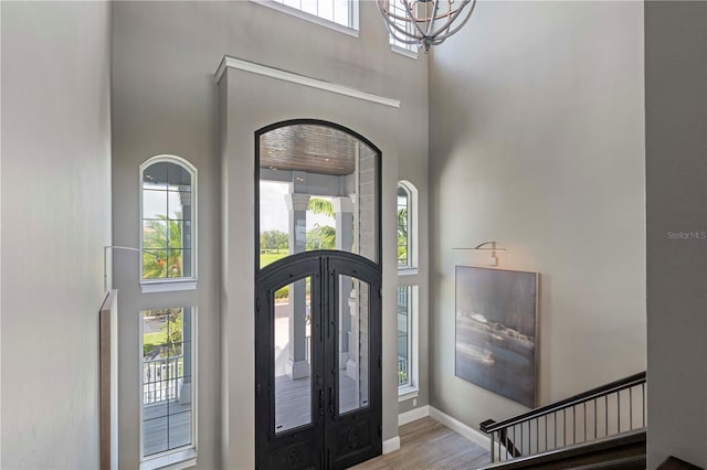 foyer with hardwood / wood-style flooring, a high ceiling, a wealth of natural light, and french doors