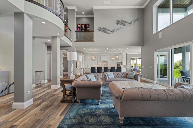 living room with wood-type flooring, ornamental molding, and a high ceiling