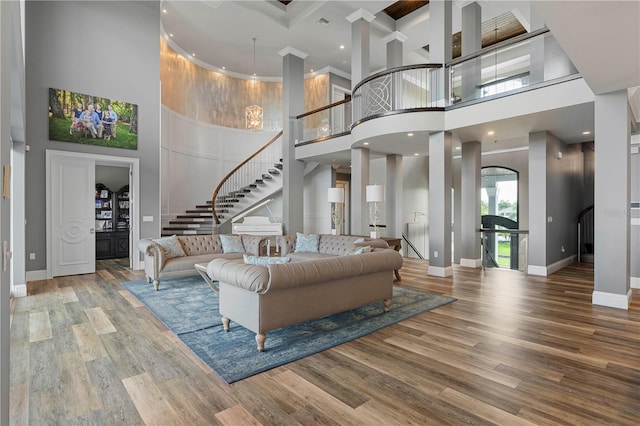 living room with beamed ceiling, a towering ceiling, hardwood / wood-style flooring, and coffered ceiling