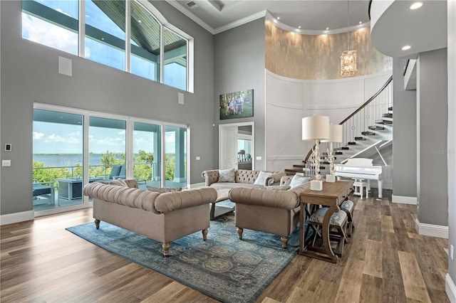 living room featuring wood-type flooring, ornamental molding, and a high ceiling