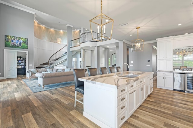 kitchen featuring light stone countertops, sink, a kitchen breakfast bar, an island with sink, and white cabinets