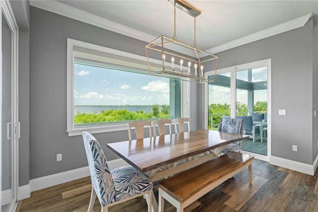 dining room with a chandelier, dark hardwood / wood-style flooring, a water view, and ornamental molding