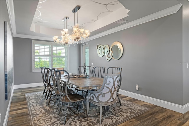 dining space with ornamental molding, a raised ceiling, dark wood-type flooring, and a notable chandelier