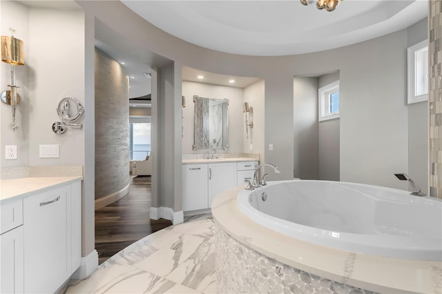 bathroom with wood-type flooring, vanity, and tiled bath