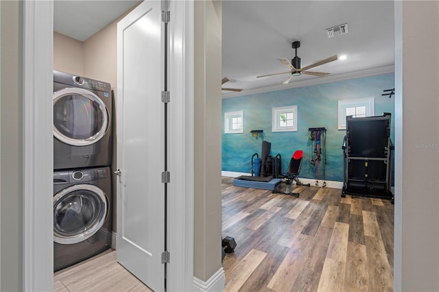 washroom with light wood-type flooring, stacked washer and dryer, ceiling fan, and ornamental molding