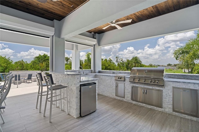 view of patio featuring area for grilling, ceiling fan, a wooden deck, and a wet bar