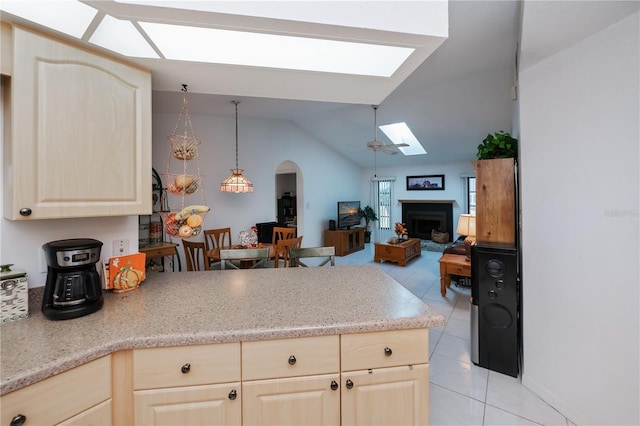 kitchen with lofted ceiling with skylight, light brown cabinets, light tile patterned floors, and decorative light fixtures