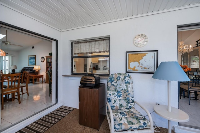 sitting room with ceiling fan with notable chandelier, light carpet, and a wealth of natural light