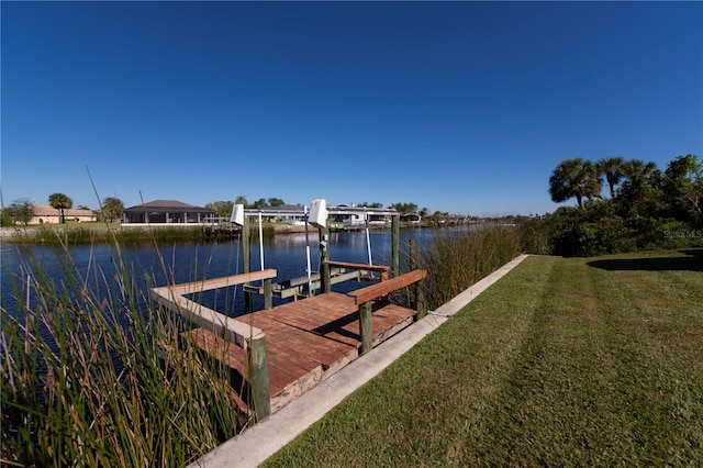 view of dock with a water view and a lawn