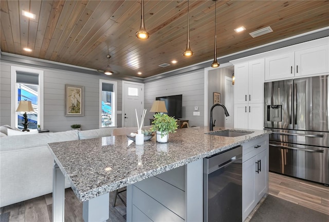 kitchen with stainless steel fridge, decorative light fixtures, a kitchen island with sink, and sink