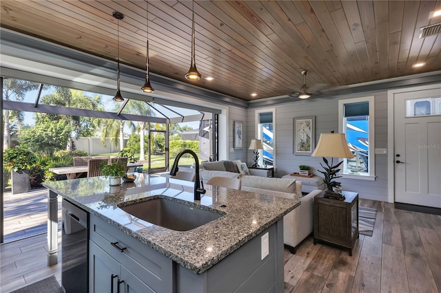 kitchen featuring pendant lighting, wood walls, sink, and a healthy amount of sunlight