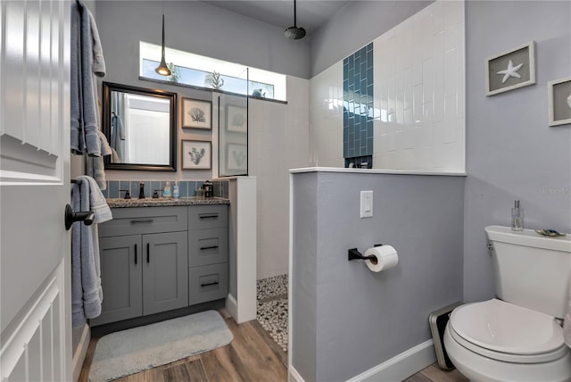 bathroom with hardwood / wood-style flooring, toilet, vanity, and walk in shower