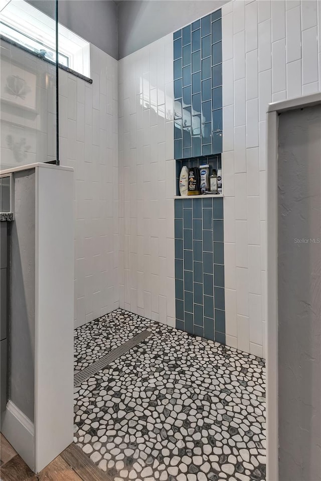 bathroom with a tile shower and hardwood / wood-style flooring