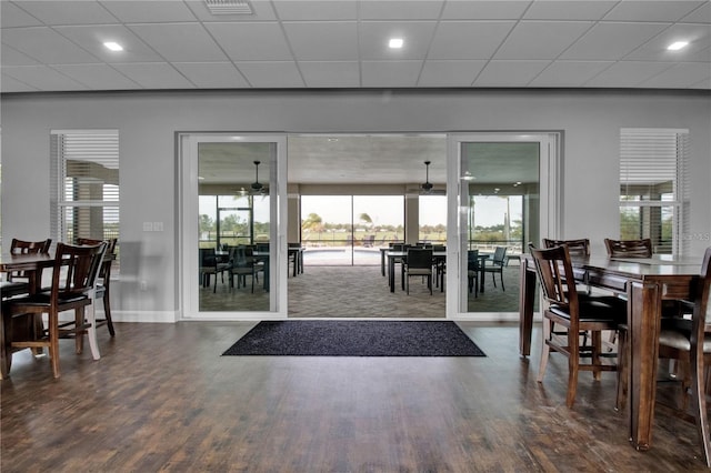 interior space with ceiling fan, a drop ceiling, and dark wood-type flooring