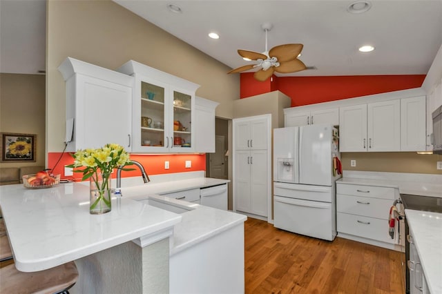 kitchen with white appliances, sink, lofted ceiling, light hardwood / wood-style floors, and a breakfast bar area