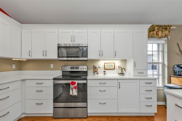 kitchen with white cabinets, stainless steel appliances, and light hardwood / wood-style flooring