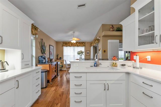 kitchen with sink, kitchen peninsula, light hardwood / wood-style flooring, ceiling fan, and white cabinetry