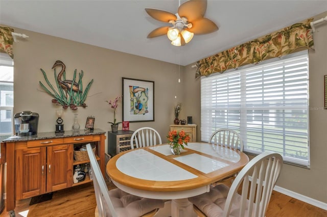 dining area with light wood-type flooring, ceiling fan, and a healthy amount of sunlight