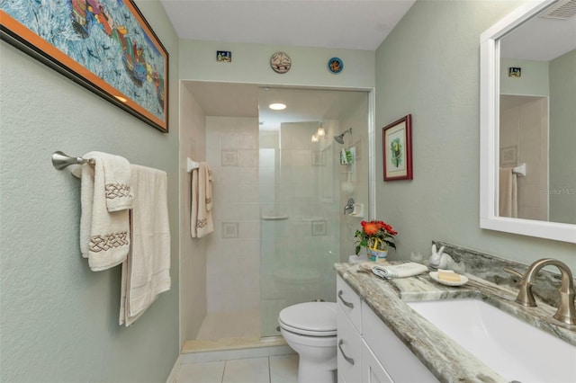 bathroom featuring tile patterned floors, vanity, toilet, and a tile shower