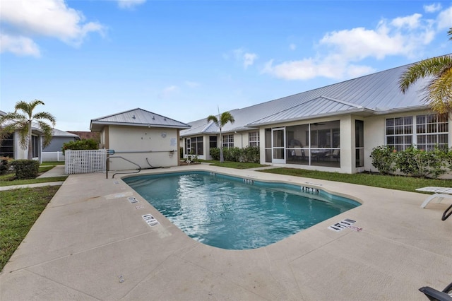 view of swimming pool with a sunroom and a patio area