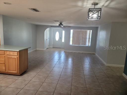 entryway featuring light tile patterned flooring and ceiling fan with notable chandelier