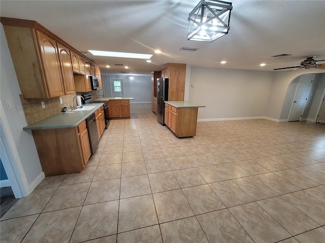 kitchen with kitchen peninsula, appliances with stainless steel finishes, backsplash, ceiling fan, and hanging light fixtures