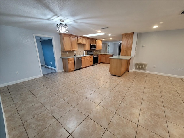 kitchen featuring sink, stainless steel appliances, kitchen peninsula, a textured ceiling, and decorative backsplash