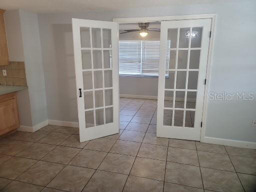 unfurnished dining area with ceiling fan, french doors, and light tile patterned flooring