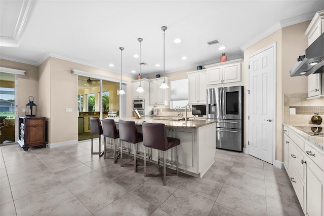 kitchen featuring pendant lighting, plenty of natural light, stainless steel fridge with ice dispenser, and a kitchen island with sink