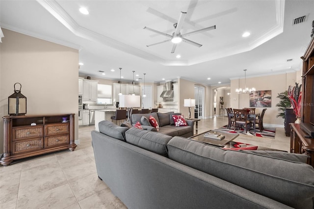 tiled living room featuring ceiling fan with notable chandelier, a raised ceiling, and crown molding