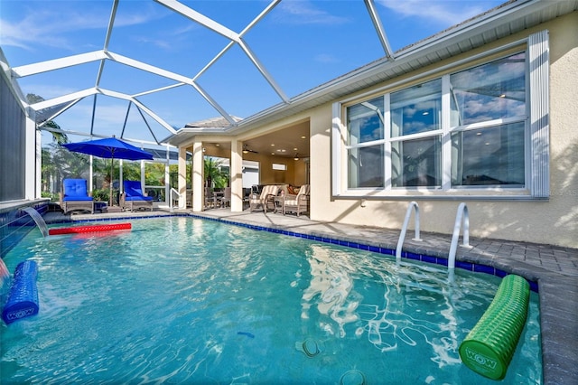 view of swimming pool with pool water feature, glass enclosure, ceiling fan, and a patio area