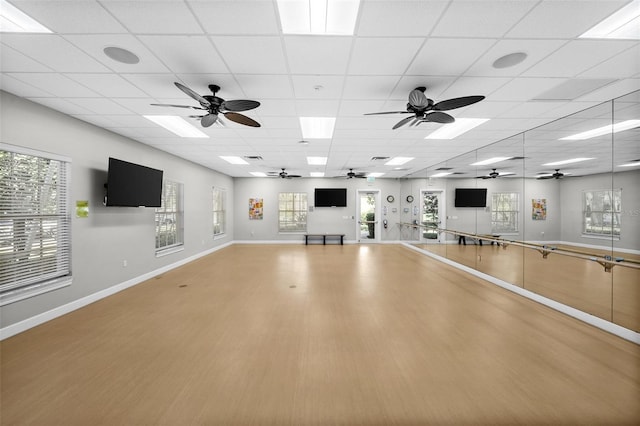 exercise room featuring a healthy amount of sunlight, hardwood / wood-style floors, and a drop ceiling