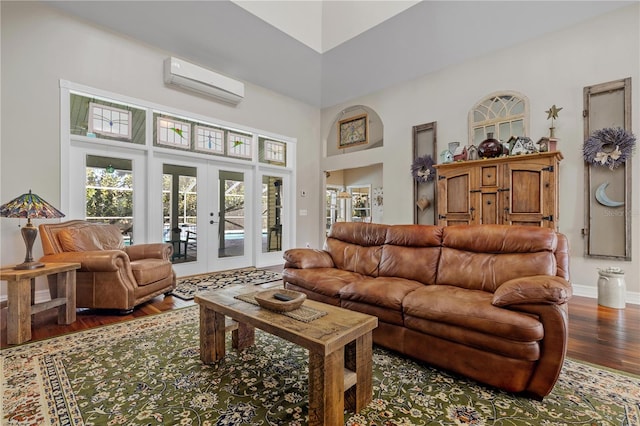 living room with a wall mounted air conditioner, french doors, dark wood-type flooring, and a high ceiling