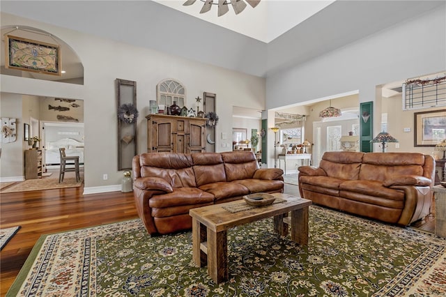 living room with wood-type flooring, a towering ceiling, and plenty of natural light