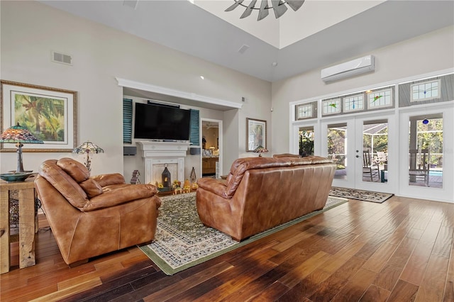 living room with french doors, a towering ceiling, hardwood / wood-style flooring, and an AC wall unit