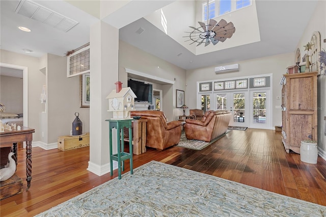 living room with a wall mounted air conditioner, hardwood / wood-style floors, french doors, and ceiling fan