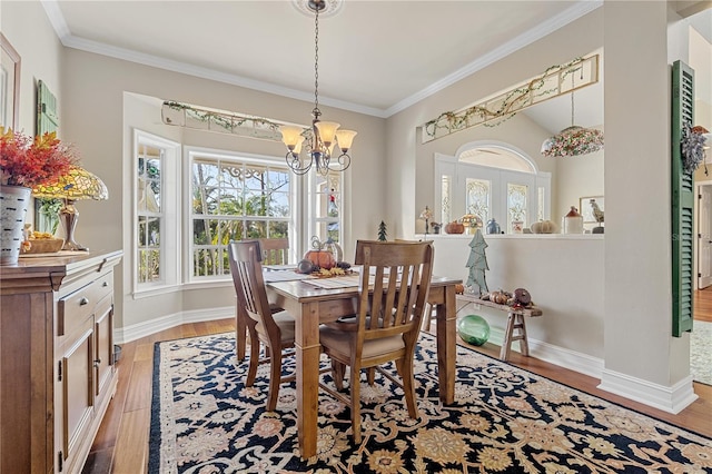 dining area featuring light hardwood / wood-style flooring, ornamental molding, and an inviting chandelier