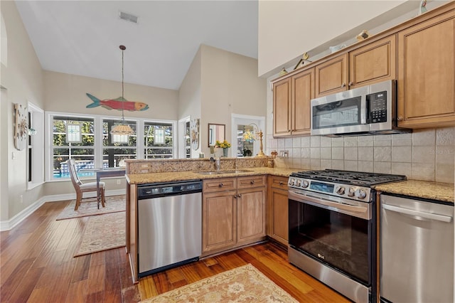 kitchen with sink, high vaulted ceiling, kitchen peninsula, hardwood / wood-style floors, and appliances with stainless steel finishes