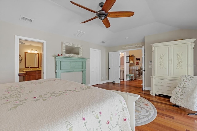 bedroom featuring hardwood / wood-style floors, ceiling fan, ensuite bathroom, and vaulted ceiling