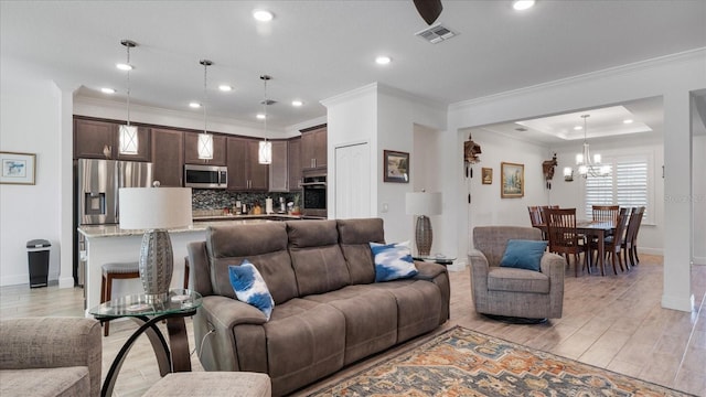 living room with light wood-type flooring, crown molding, and a notable chandelier