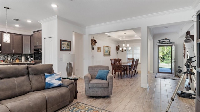 living room with an inviting chandelier, crown molding, and light hardwood / wood-style flooring