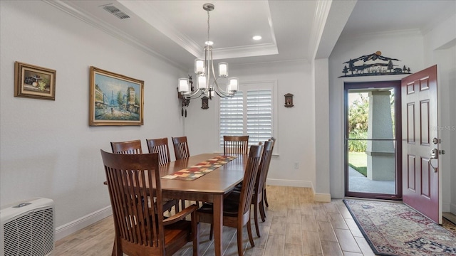 dining area featuring an inviting chandelier, crown molding, light hardwood / wood-style flooring, and a tray ceiling