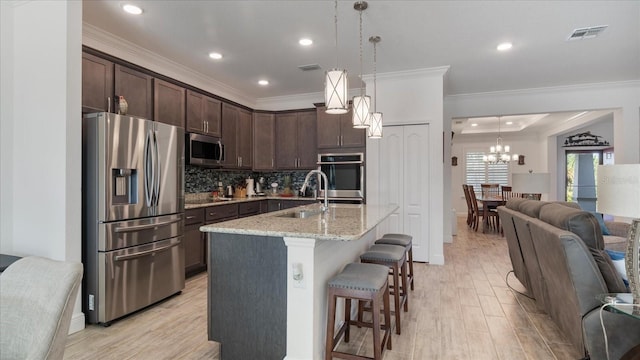 kitchen with decorative light fixtures, light stone counters, dark brown cabinets, and appliances with stainless steel finishes