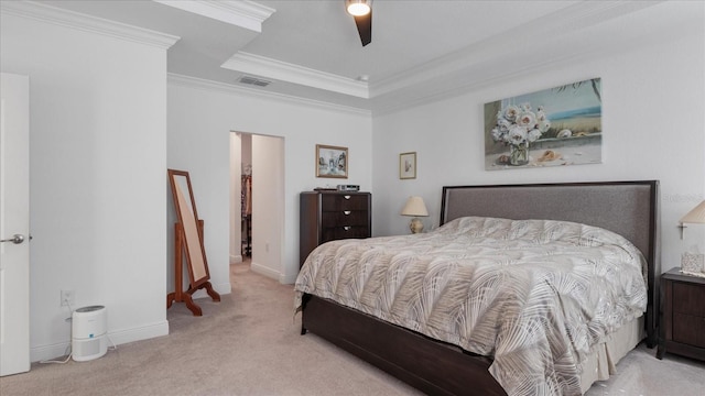 carpeted bedroom featuring a tray ceiling, a spacious closet, ceiling fan, and crown molding