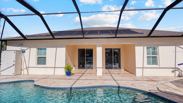 back of property with a patio area, glass enclosure, and solar panels