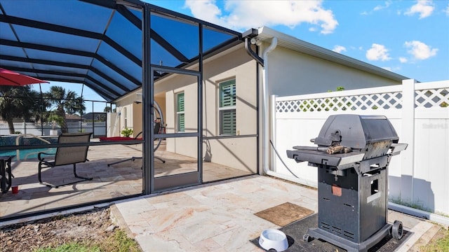 view of patio featuring glass enclosure and area for grilling