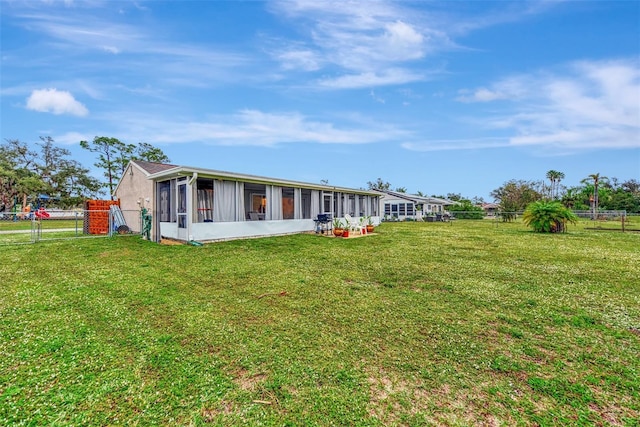 rear view of property featuring a yard and a sunroom