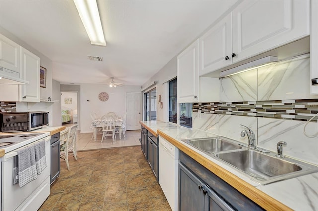 kitchen with backsplash, white appliances, white cabinets, and sink